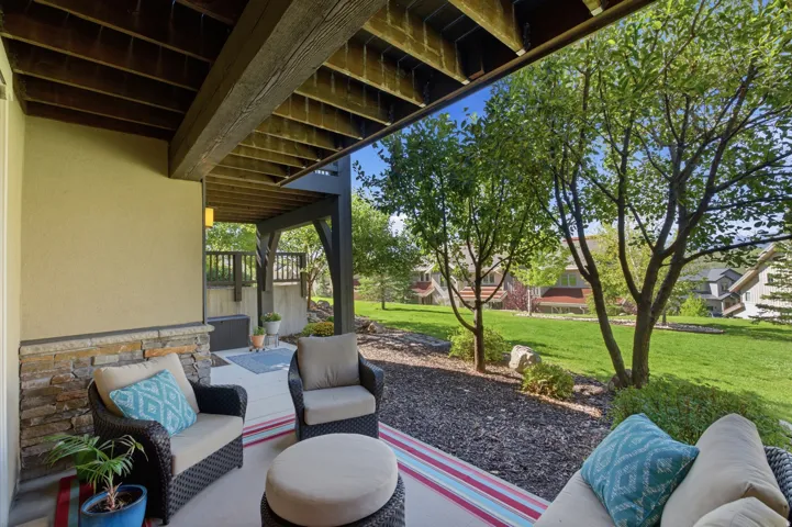 Covered patio with a stucco exterior, stone veneer accents, and an exposed wood beam ceiling