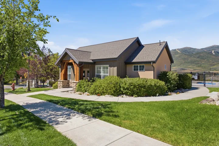 Gabled roofline structure with stone and wood column accents, surrounded by manicured lawns and mature landscaping