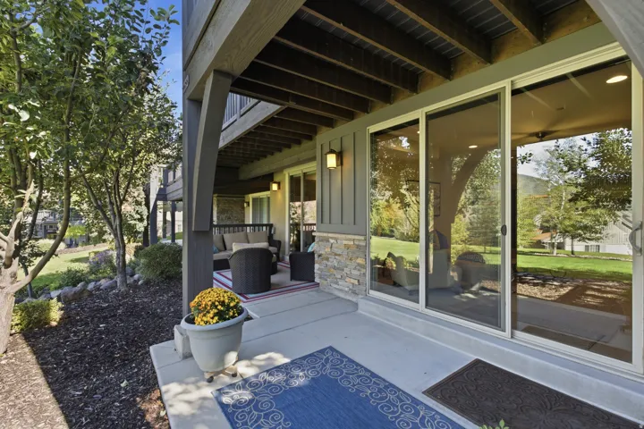 Concrete patio with stacked stone accents, board and batten siding, and dual sliding glass doors