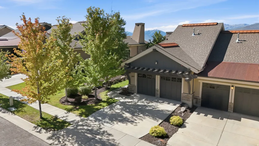 Stone and siding exterior with multiple garage bays, a pergola accent, and a shingle roof