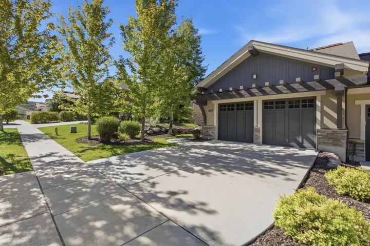 Two-car garage with a pergola-style accent, stone facade elements, and a concrete driveway