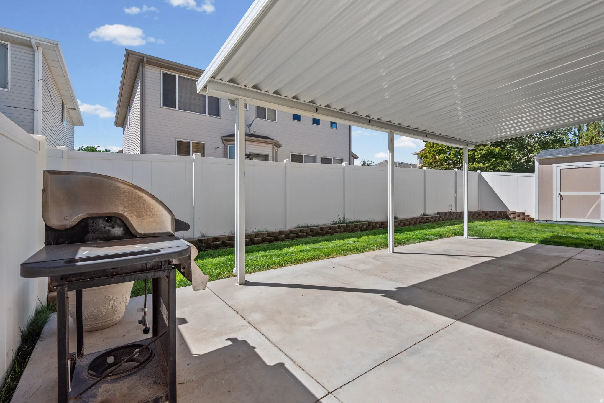Covered patio with concrete flooring, private fencing, and a built-in storage shed