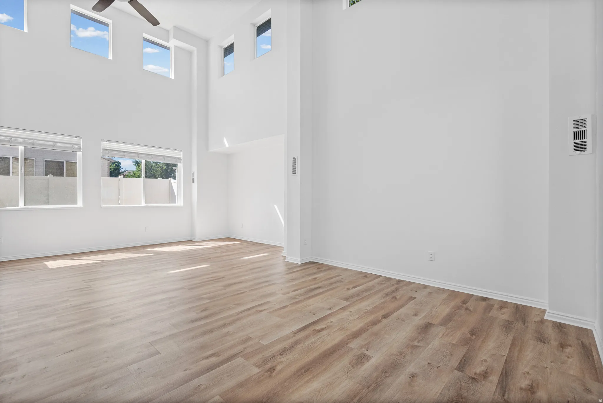 Vaulted ceilings, wood-finish flooring, high-set windows, and a ceiling fan