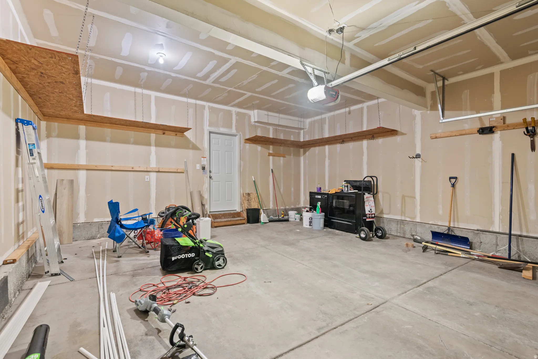 Spacious garage featuring concrete flooring, an overhead garage door opener, and built-in shelving for organization
