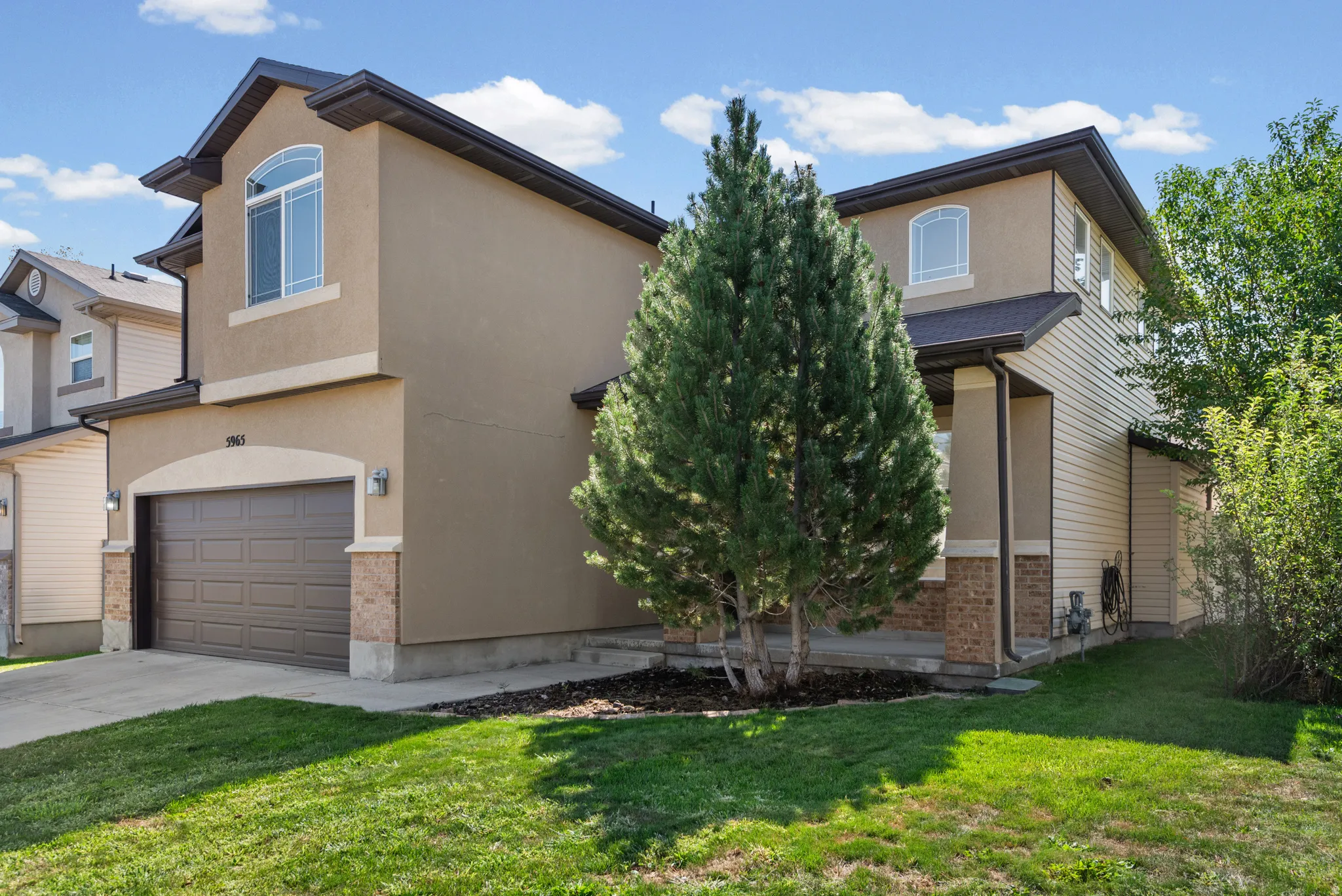 Two-story stucco and siding exterior with a prominent arched window, attached garage, and concrete driveway