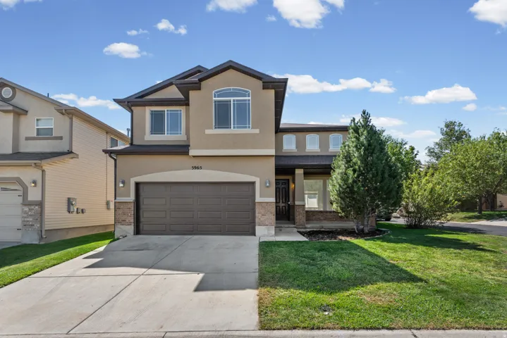 Two-story stucco exterior with stone accents, attached two-car garage, concrete driveway, covered entry porch, and arched windows