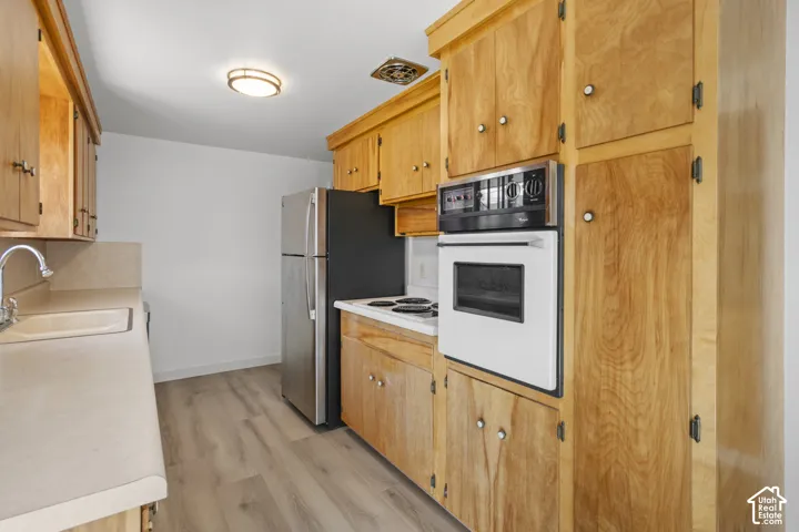 Kitchen featuring wood-finish cabinetry, light-toned countertops, and wood-finish flooring
