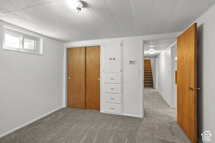 Gray carpet flooring, white painted walls, wood-finish sliding closet doors, and built-in storage cabinetry