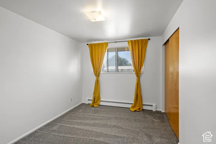 Recessed window with baseboard heating, neutral wall paint, ceiling-mounted light fixture, and carpeted flooring