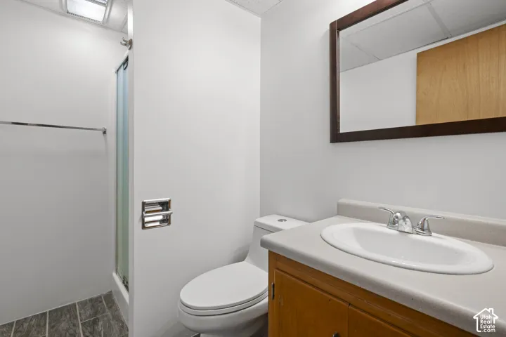 Bathroom featuring a wood-finish vanity with an integrated sink, framed mirror, and a shower with a sliding glass enclosure