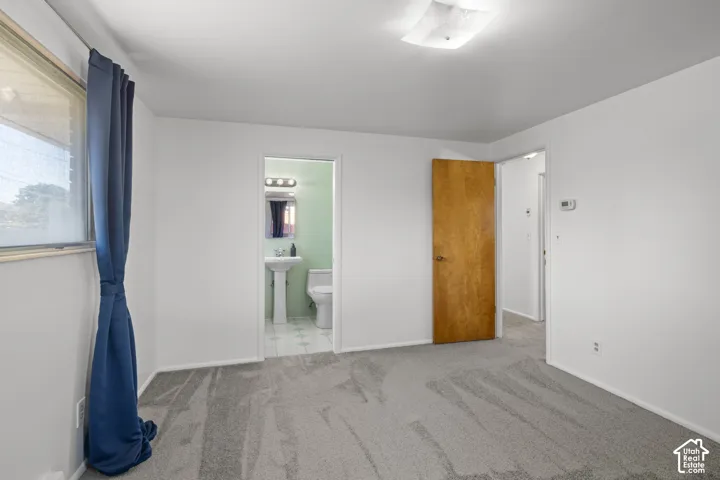 Light-toned carpeted flooring, white painted walls, and a ceiling-mounted light fixture