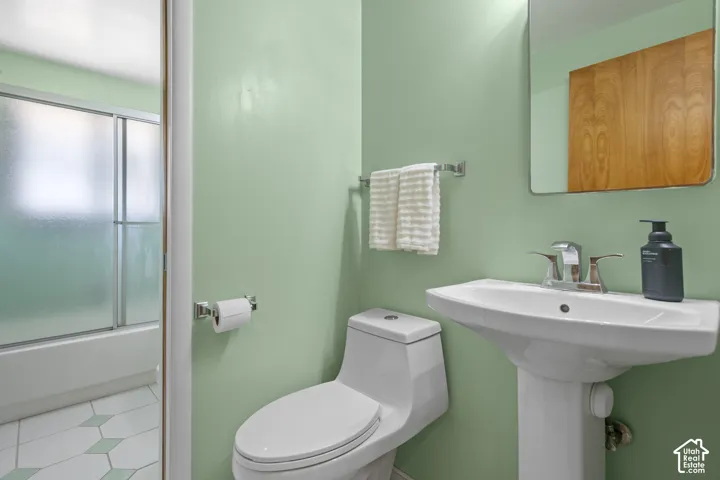 Pedestal sink with chrome faucet, wall-mounted mirror, and a white toilet