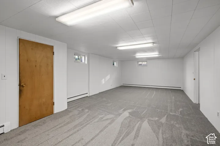 Spacious room with white paneling, patterned gray carpet, and two fluorescent light fixtures