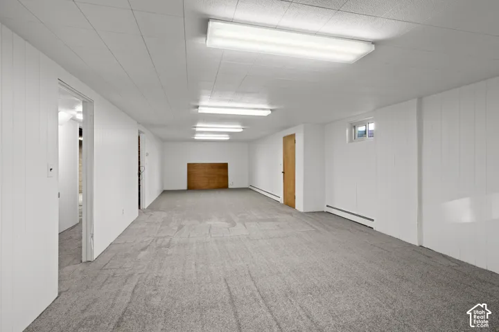 Expansive room with carpet flooring, white paneled walls, and a recessed ceiling
