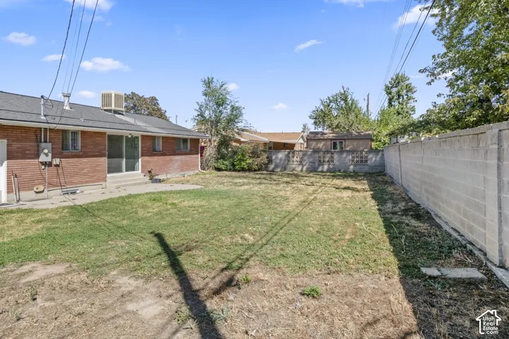 Expansive backyard featuring a concrete patio and a block privacy wall