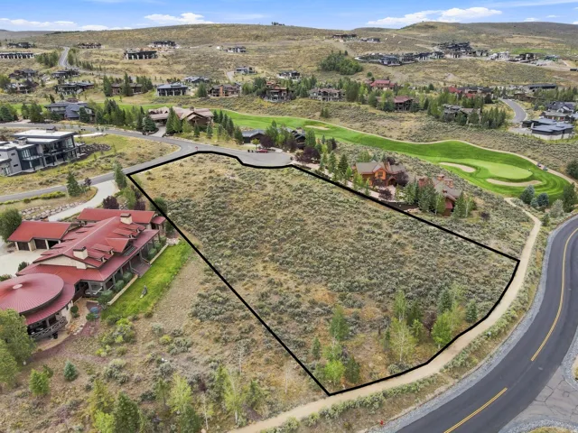 Expansive lot with natural landscaping, bordered by a paved road