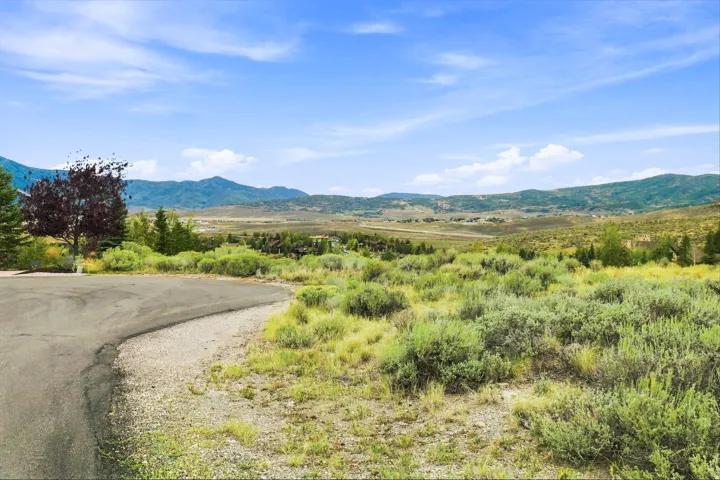 Expansive land parcel featuring natural shrubbery and distant mountain formations