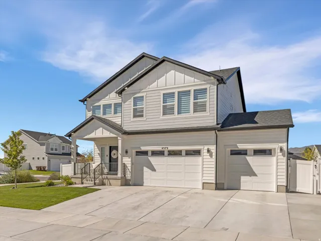 Contemporary two-story residence with a covered entry, multiple garage bays, and a well-maintained lawn
