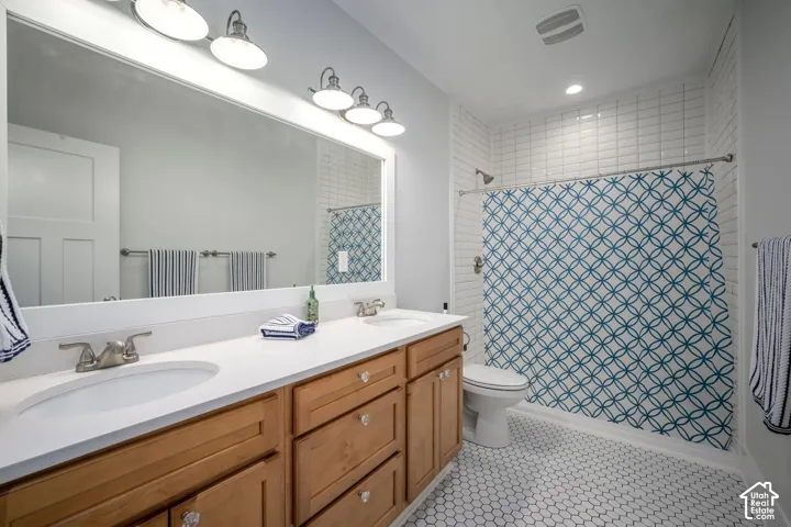 Dual vanity with wood-finish cabinetry, white countertop, and brushed nickel fixtures