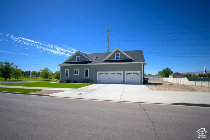 Grey siding exterior with a dark shingle roof, twin gabled dormers, and a two-car garage