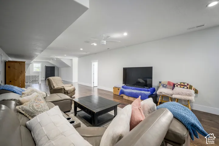 Recessed ceiling lighting, wood-finish flooring, ceiling fan, white interior walls, and an open doorway