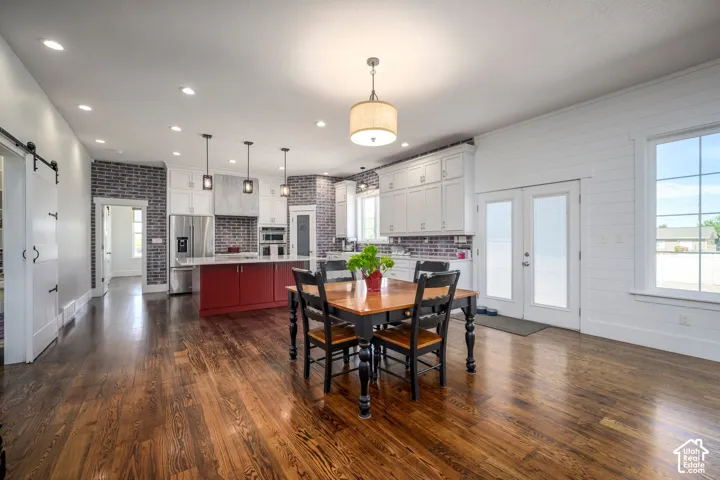 Expansive open-concept living area featuring wood-finish flooring, recessed lighting, and a kitchen island with a white countertop and red cabinetry