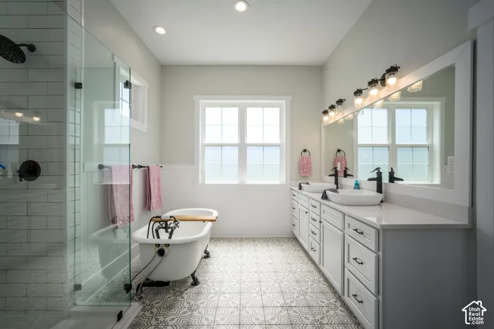 Dual vanity with vessel sinks, a standalone soaking tub, and a glass-enclosed shower with subway tile