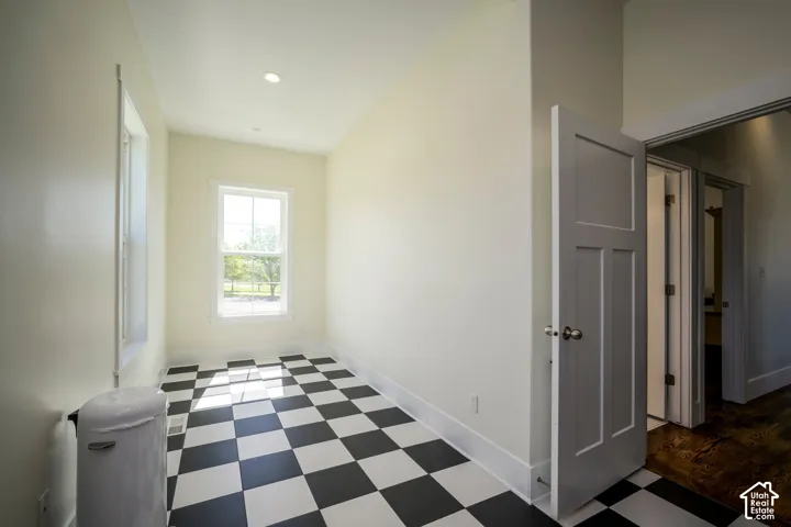Black and white checkerboard flooring, recessed lighting, and a white paneled door