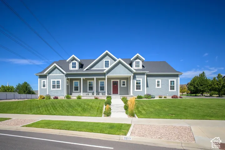Two-story residence featuring light gray siding with white trim, a dark gray shingle roof, and multiple dormers