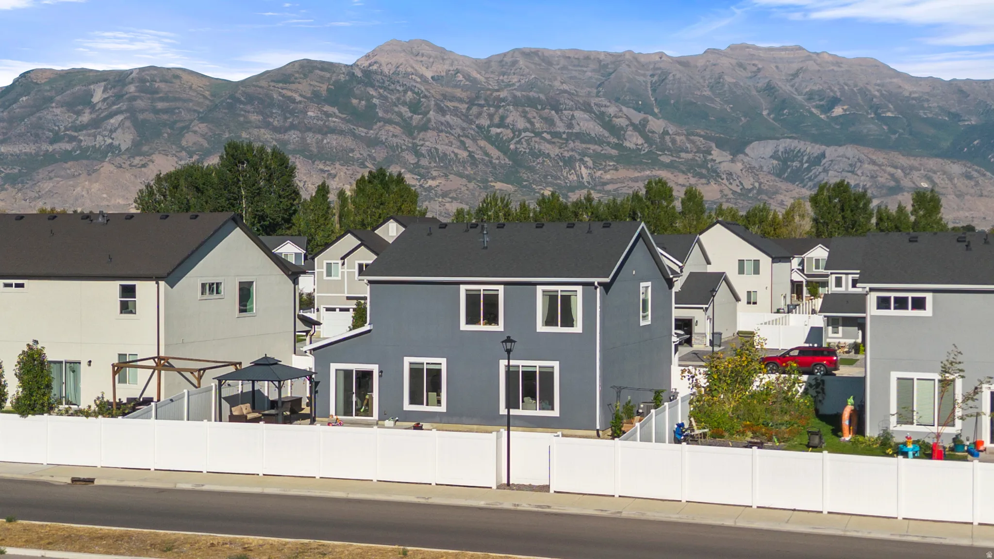 Contemporary residence featuring a dark gray exterior, white window trim, and a dark shingle roof