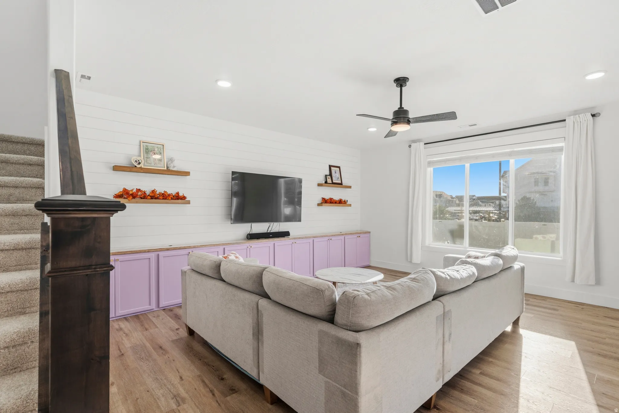 Wood-finish flooring, built-in cabinetry, large window, ceiling fan, and recessed lighting