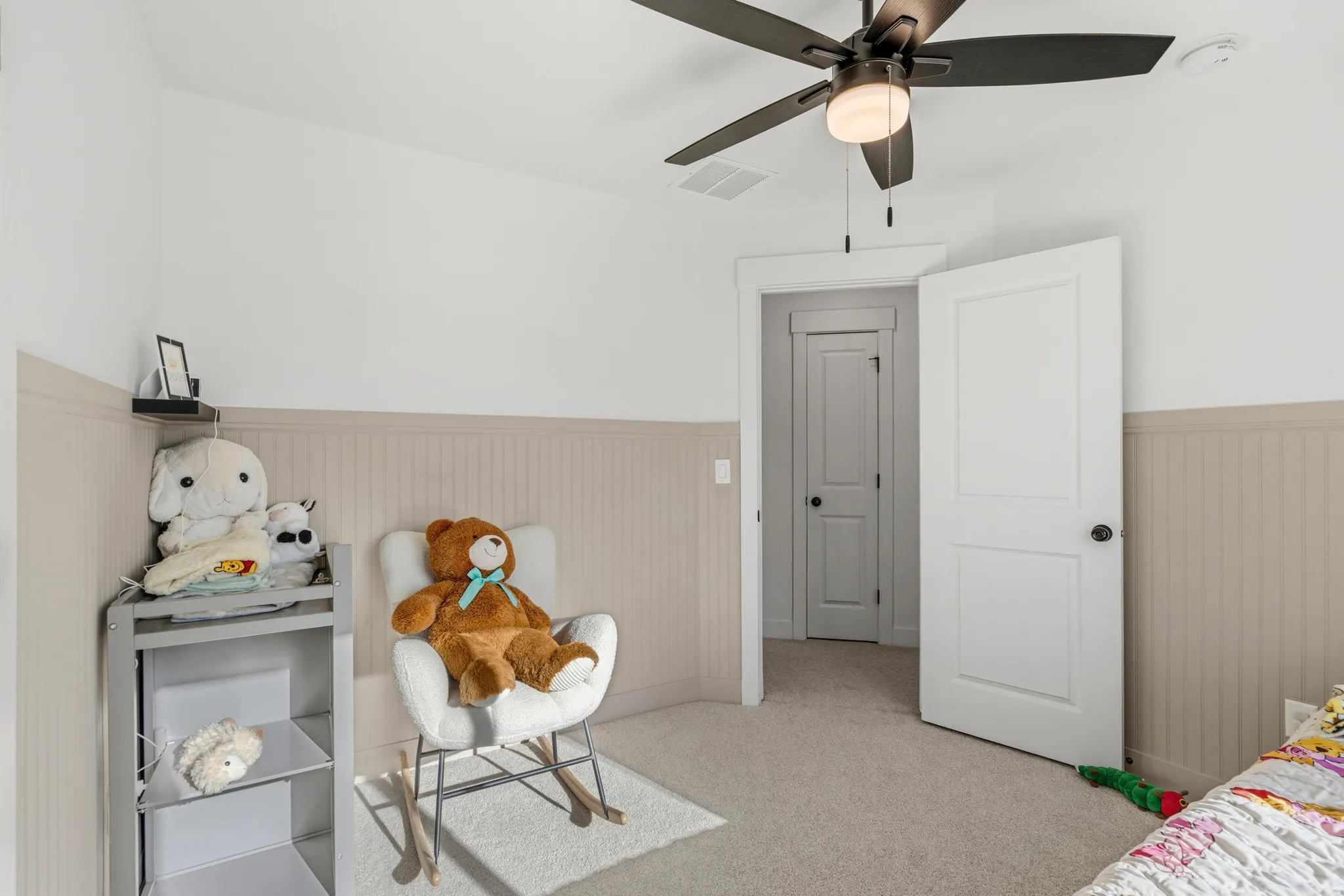 Wall-to-wall carpeting, two-panel interior doors, beadboard wall paneling, and a ceiling fan with integrated lighting