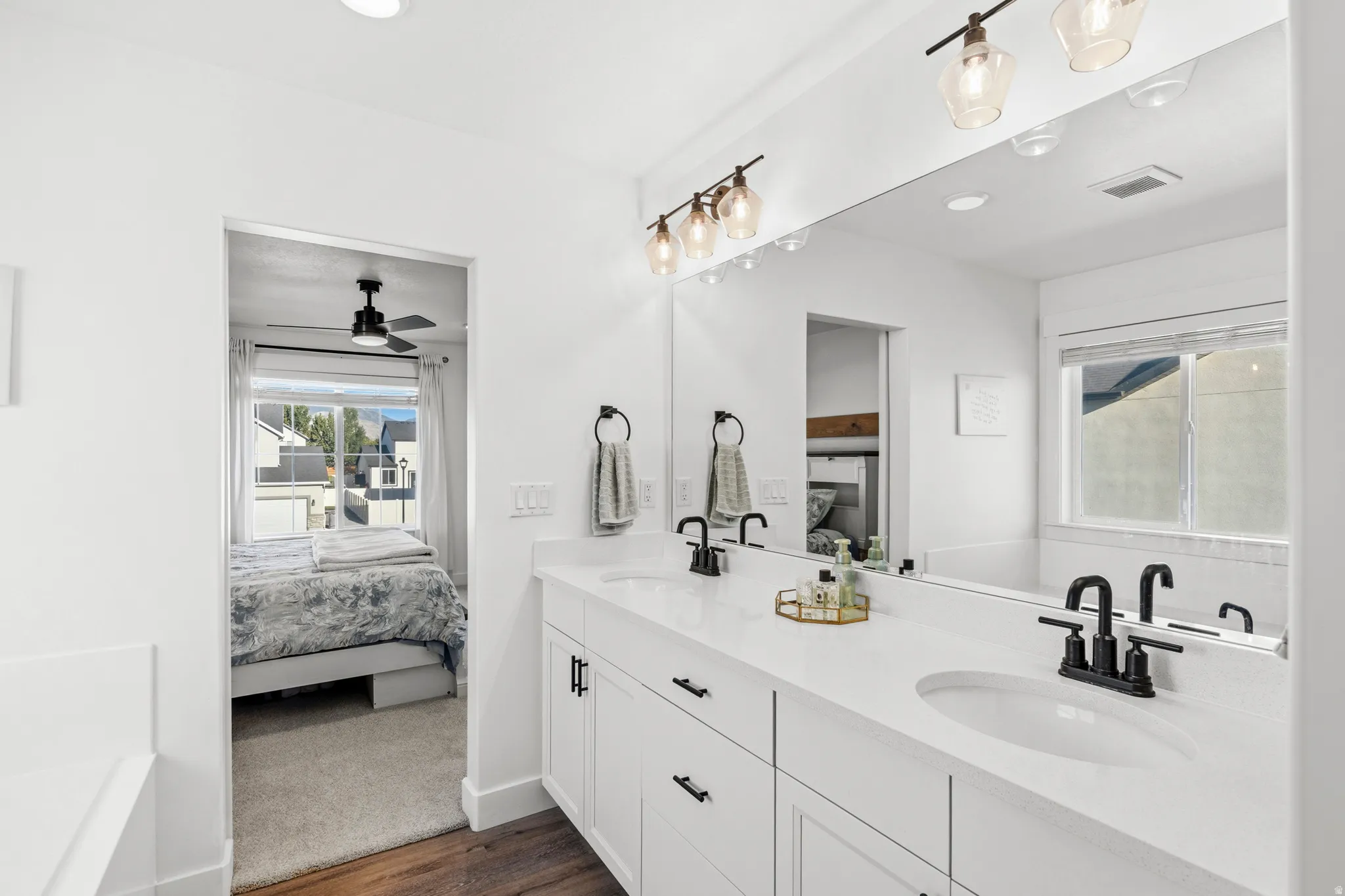 Dual vanity with white cabinetry, matte black fixtures, and a large wall-mounted mirror