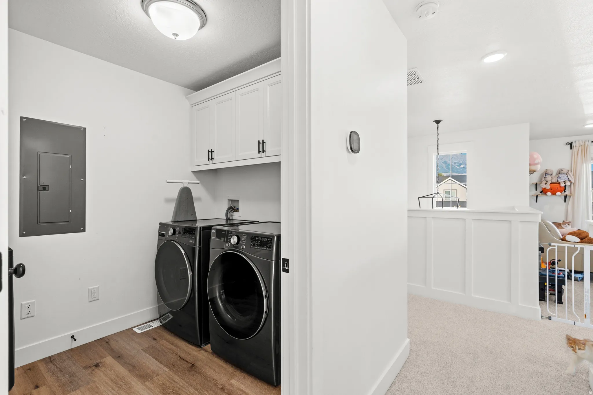 Wood-finish flooring with white baseboards, built-in white cabinetry with dark hardware, and a ceiling-mounted light fixture