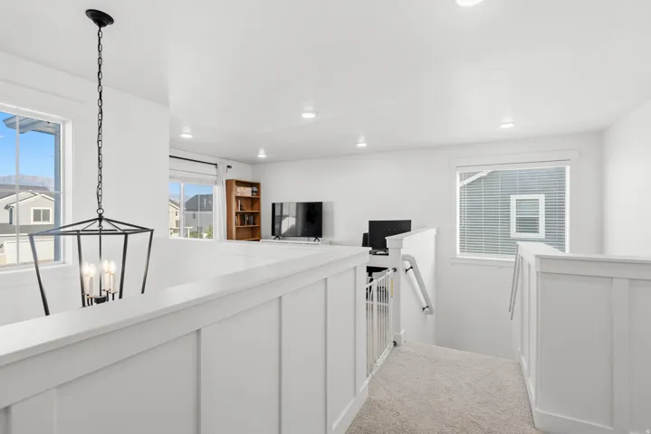 Upper-level landing with white board and batten railing, recessed lighting, and a contemporary black lantern pendant light