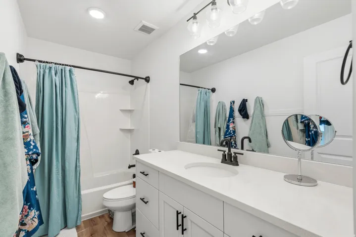 White vanity with a neutral countertop, undermount sink, and black-finish faucet
