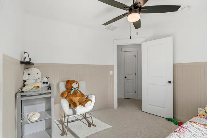 Wall-to-wall carpeting, two-panel interior doors, beadboard wall paneling, and a ceiling fan with integrated lighting