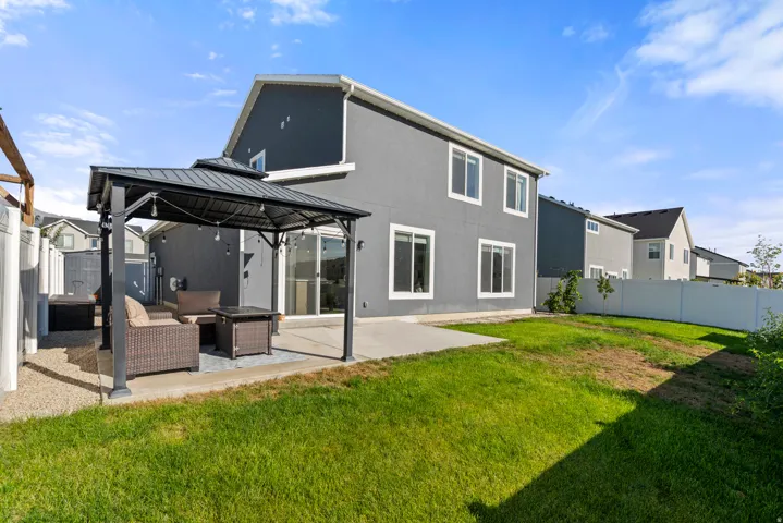 Rear exterior with gray stucco siding, white window trim, and a white privacy fence