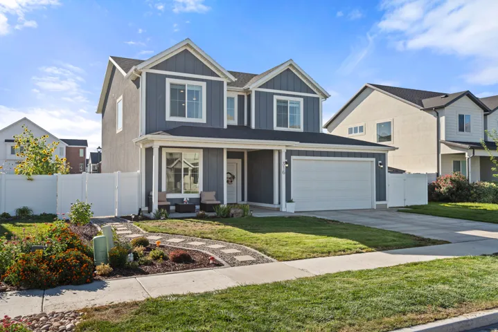 Two-story residence featuring a two-car garage, covered porch, and front landscaping