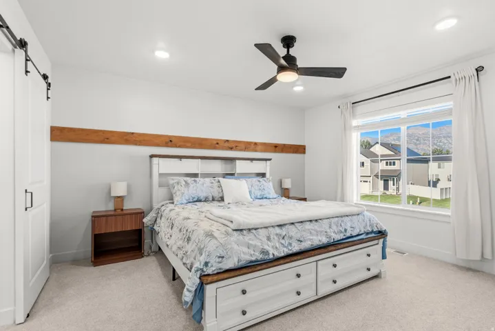 Tray ceiling with recessed lighting, ceiling fan, and a barn door entry