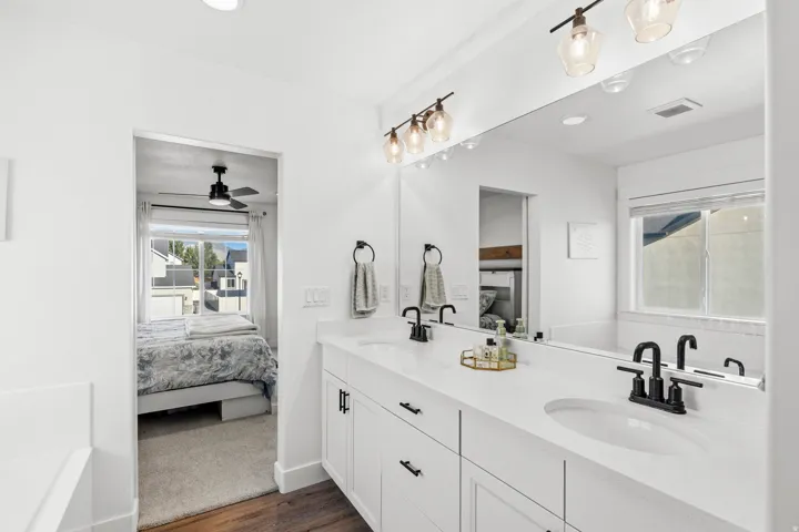 Dual vanity with white cabinetry, matte black fixtures, and a large wall-mounted mirror