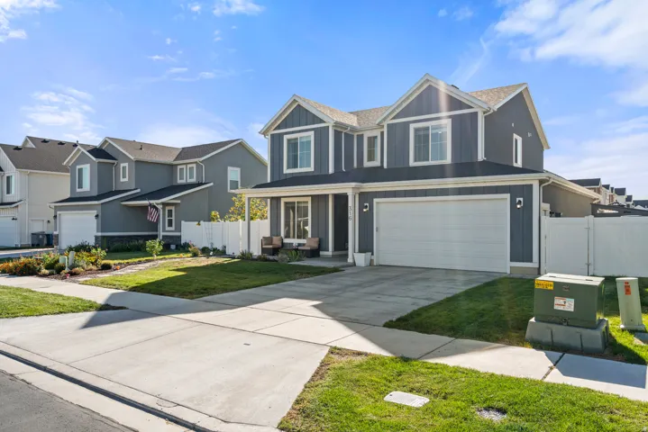 Contemporary two-story exterior with dark gray siding, white trim, a covered porch, and an attached two-car garage