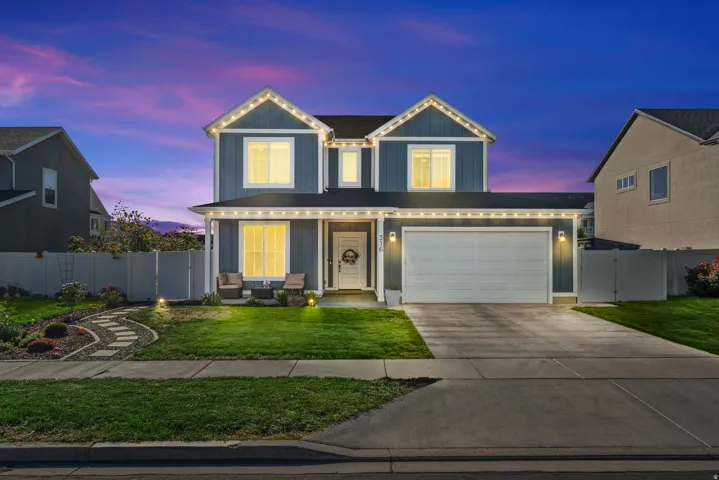 Two-story residence with a two-car garage, concrete driveway, front porch, and a stone-paver walkway