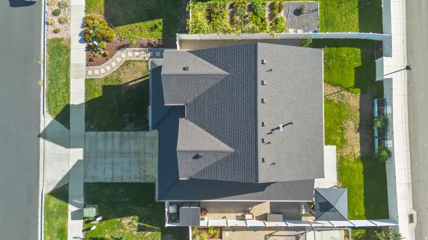 Asphalt shingle roofing, concrete driveway, and a front yard with a stone-lined pathway