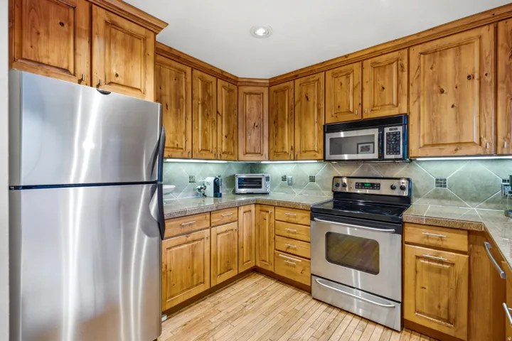 Kitchen with wood cabinetry, stainless steel appliances and recessed lighting