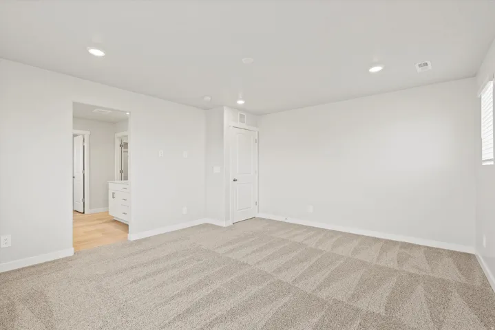 Recessed lighting, patterned carpeting, white walls, and a window with blinds