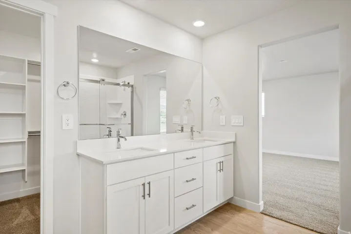 Dual vanity with white cabinetry, integrated sinks, chrome fixtures, and a large wall-mounted mirror