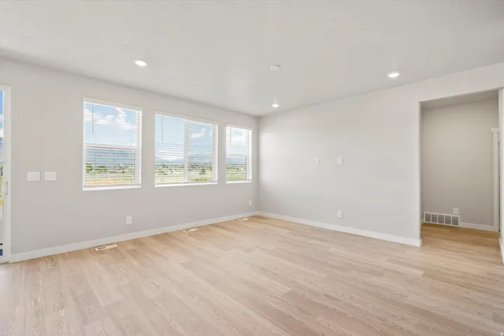Light-toned wood-finish flooring, recessed lighting, multiple windows with blinds, and white wall finishes