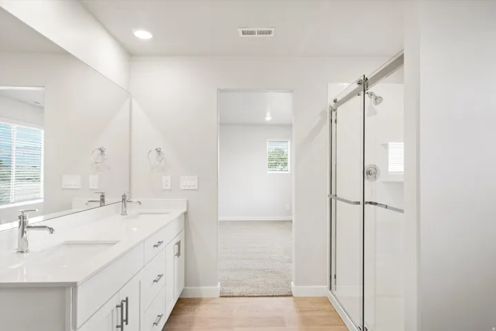 Double vanity with white cabinetry and chrome hardware, white solid surface countertops, and dual rectangular undermount sinks