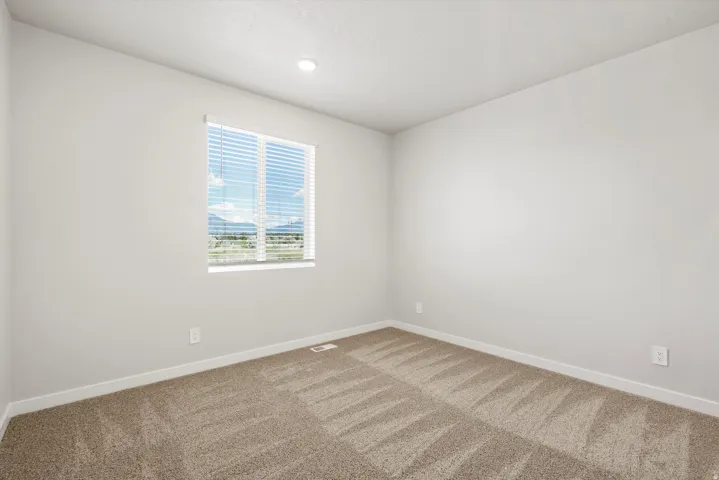Recessed lighting, neutral wall tones, window with horizontal blinds, patterned carpet flooring, and mountain scenery